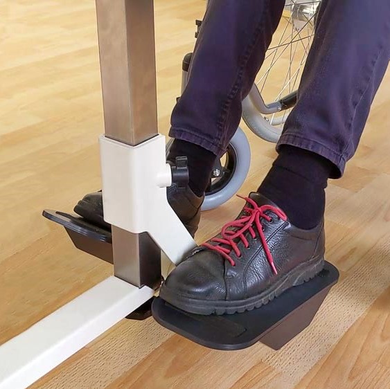 Füße in schwarzen Schuhen einer Frau im Rollstuhl stehen auf der Plaudertisch-Nähmaschine