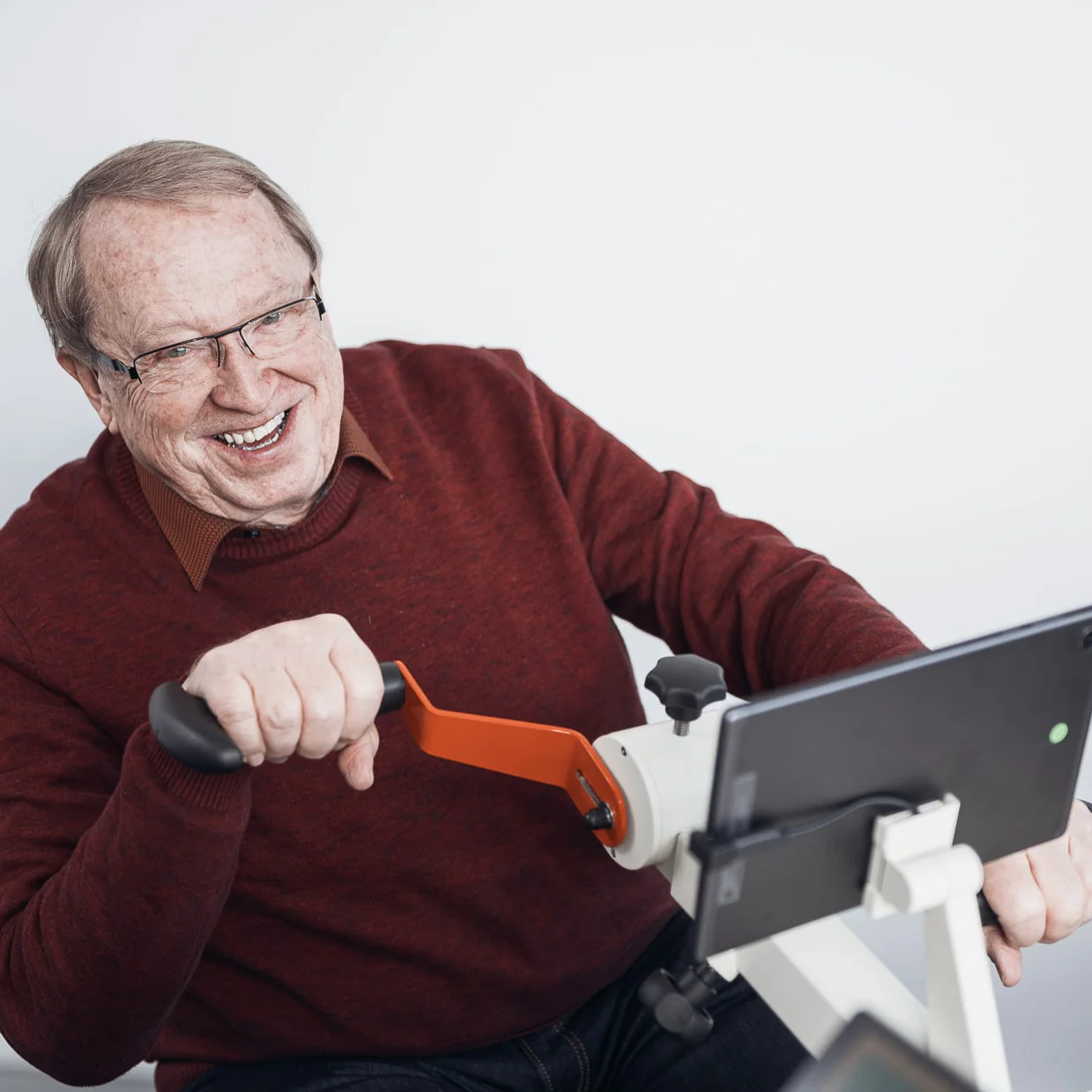 Senior sitzt lachend am digitalen Plaudertisch
